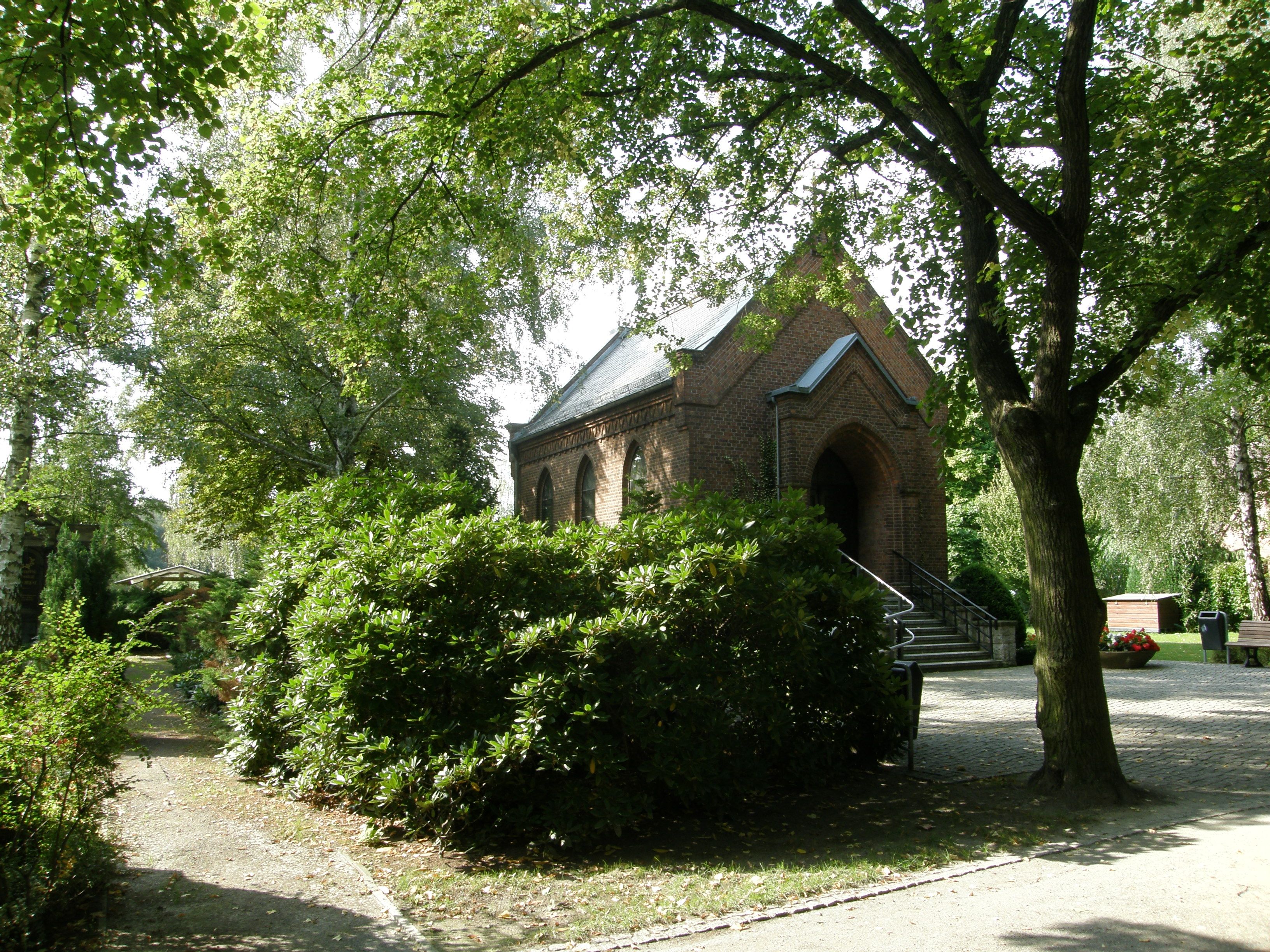 Backsteinkapelle mit Treppe unter Bäumen auf dem Friedhof Biesdorf