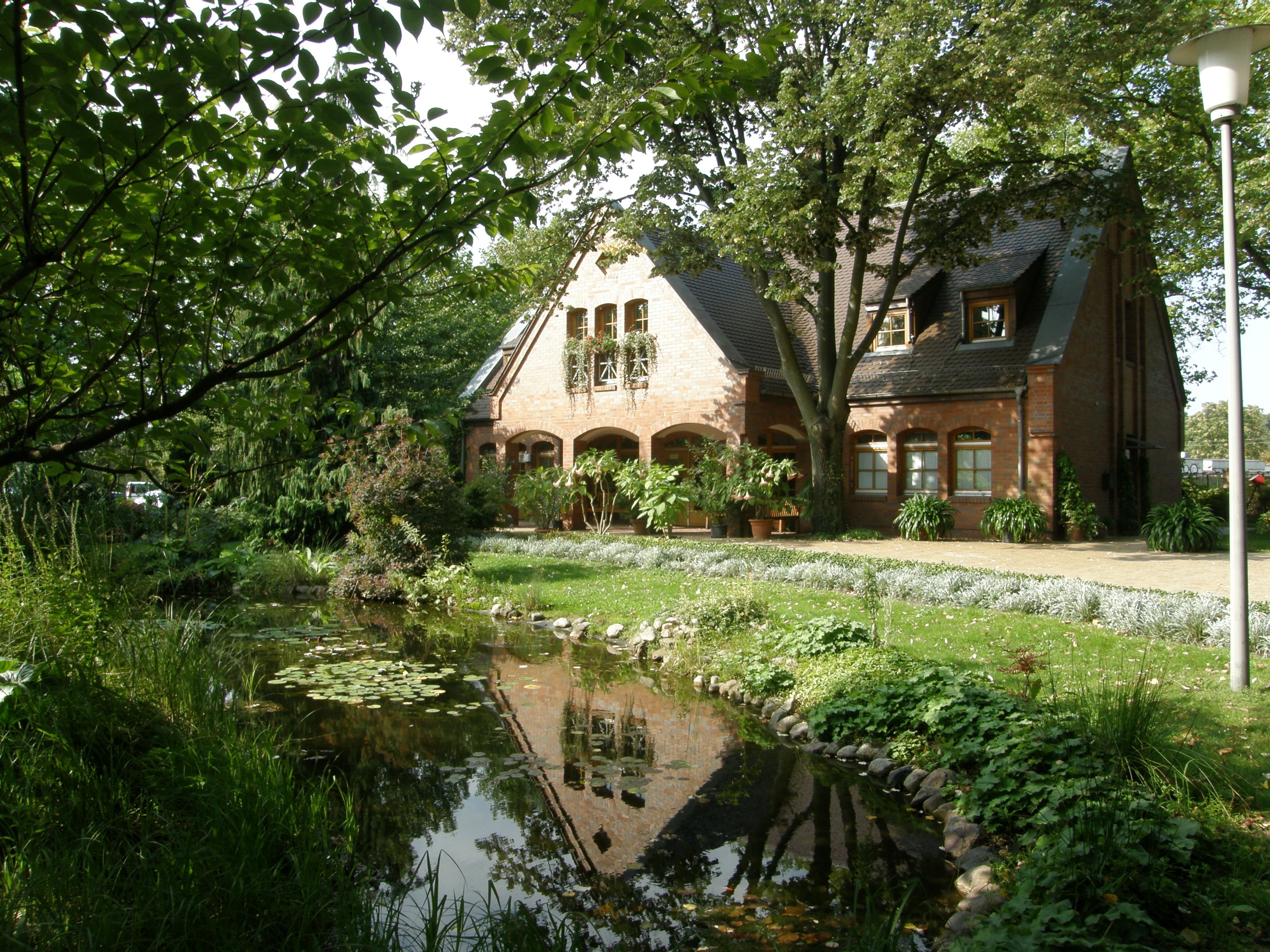 Backsteingebäude und Teich im Eingangsbereich des Friedhofs Biesdorf
